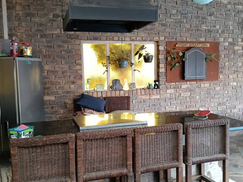 Covered outdoor patio area featuring an exposed brick wall, built-in extractor hood, and a tiled floor, ideal for outdoor entertaining.