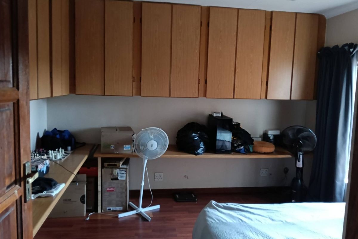 Bedroom featuring extensive built-in wooden cabinetry and a integrated desk workspace with laminate flooring.