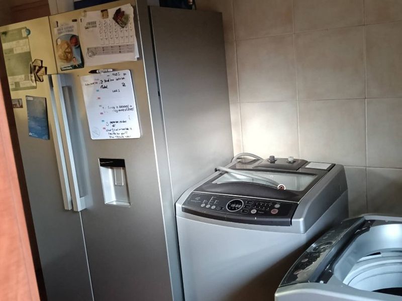 A functional laundry area featuring tiled walls and flooring, equipped with space for major appliances.