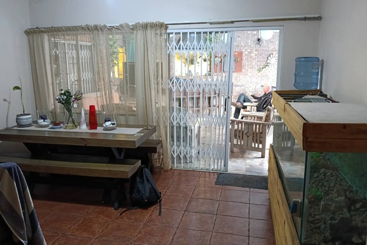 Living area featuring terracotta floor tiles and a sliding glass door with a security gate leading to an outdoor patio space.