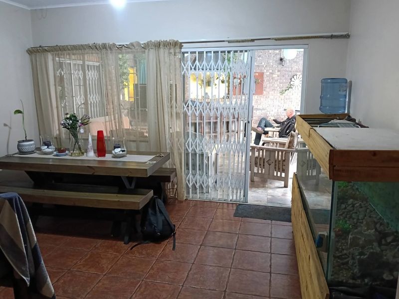 Living area featuring terracotta floor tiles and a sliding glass door with a security gate leading to an outdoor patio space.