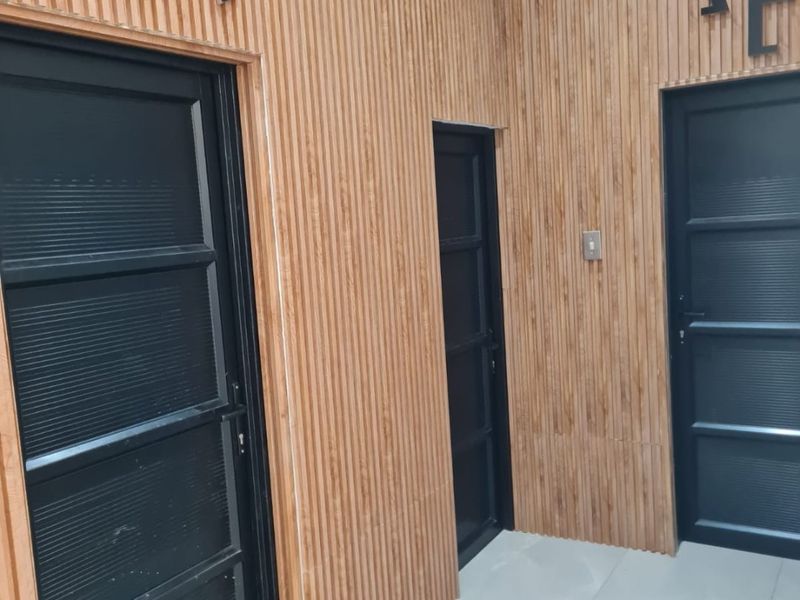 A modern commercial hallway featuring slatted timber wall paneling, large format floor tiles, and clearly marked accessible restroom entrances.