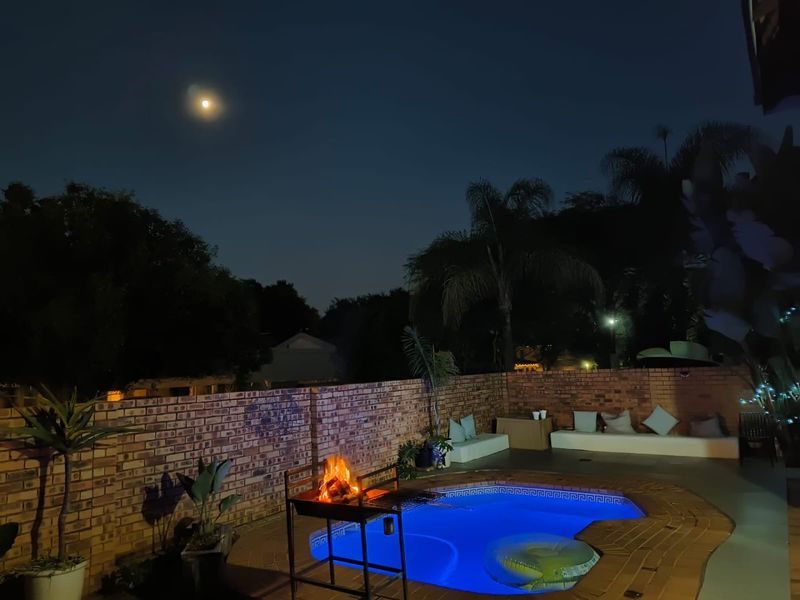 Night view of a private swimming pool area featuring brick paving and a surrounding brick boundary wall, perfect for evening outdoor relaxation.
