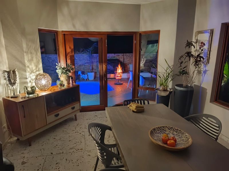 Dining area featuring terrazzo flooring and wooden framed glass sliding doors providing direct access to the outdoor pool area.