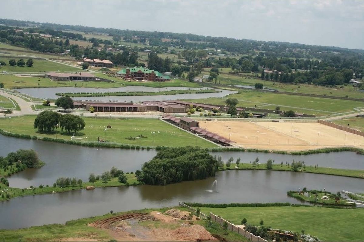 An expansive aerial view of a large residential estate featuring multiple lakes, manicured green spaces, and established equestrian infrastructure.