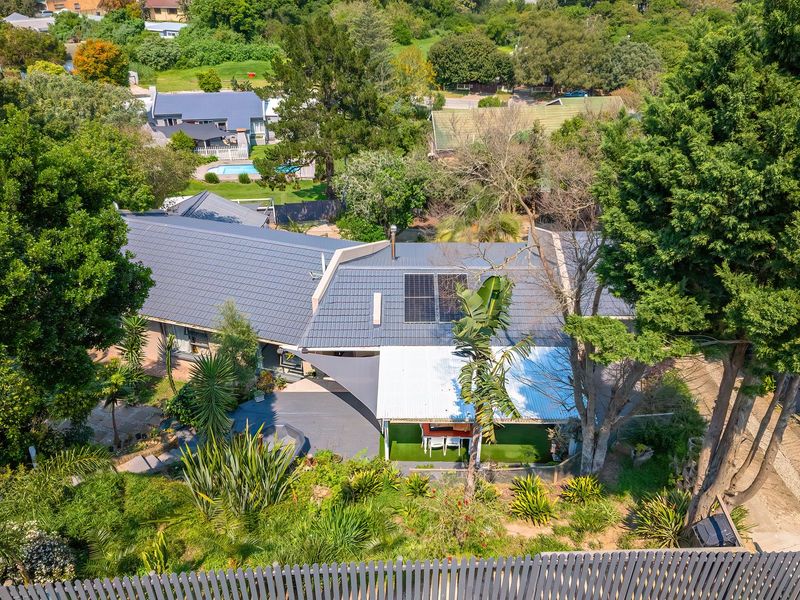 Aerial view of the property showcasing the roof structure, solar panels, covered patio area, and established garden surroundings.