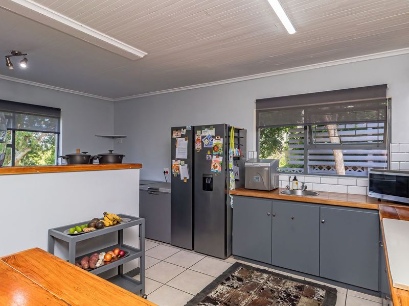 A functional kitchen featuring grey cabinetry, timber countertops, subway tile backsplash, and tiled flooring, offering a clean and practical workspace.