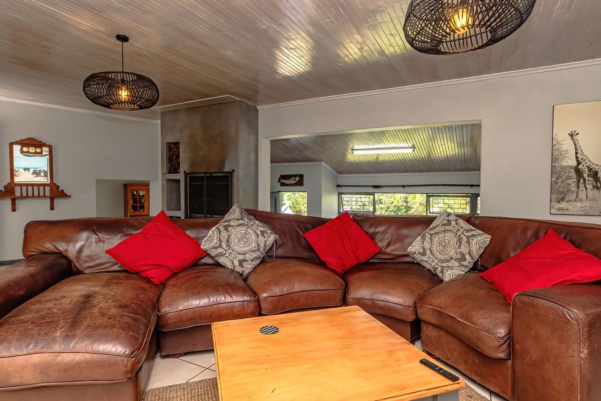 Spacious living room featuring a built-in fireplace, classic tongue and groove ceiling, and neutral tiled flooring.