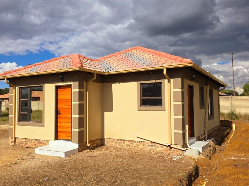 A newly constructed single-story house featuring a tiled roof, neutral exterior paint, and aluminium window frames, currently awaiting final landscaping.