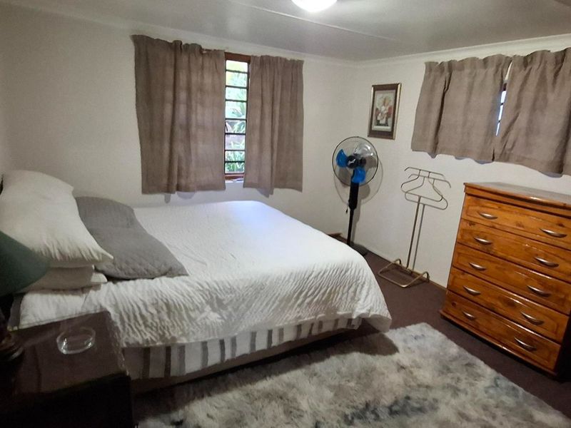 A functional bedroom featuring neutral walls, two windows with curtains, and standard flooring, offering a comfortable and well-lit sleeping space.