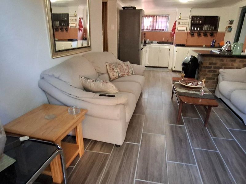 Open plan living area featuring tiled flooring and a kitchen with a brick breakfast bar and built-in cabinetry.