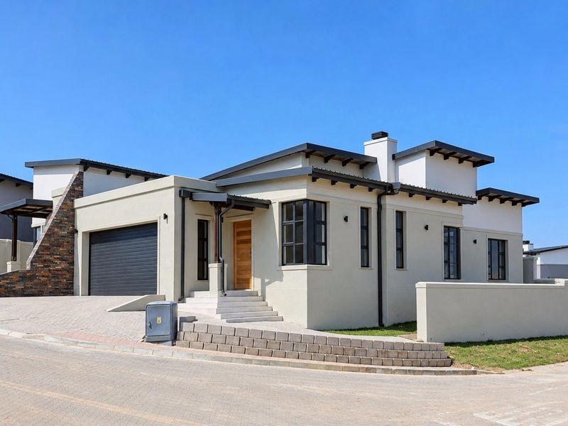 Modern single-story residence featuring a double garage, stone-clad accent wall, timber entrance door, and clean architectural lines with a paved driveway.