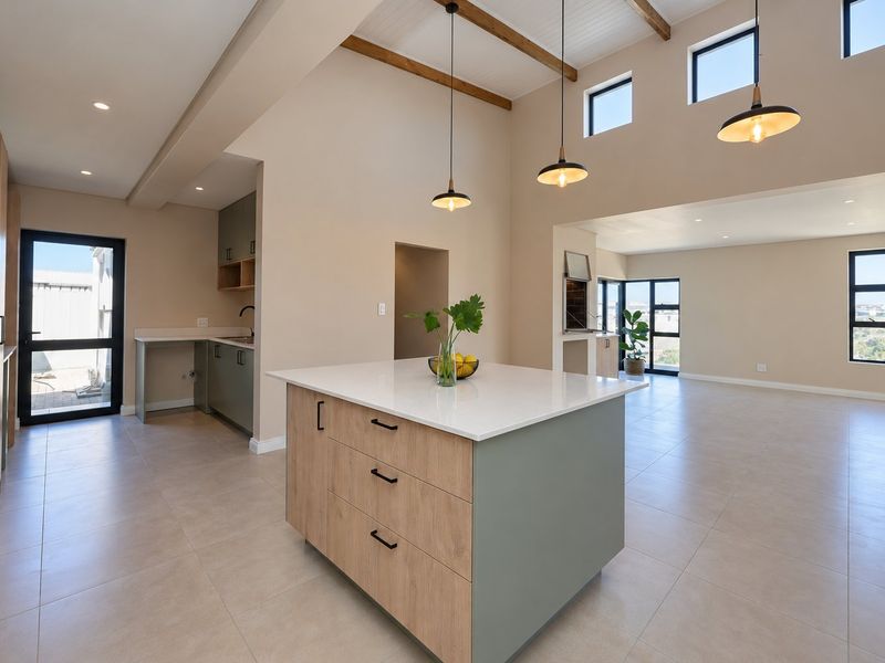 Spacious open-plan kitchen and living area featuring a central island, modern cabinetry, exposed timber beams, and a built-in braai with high ceilings.