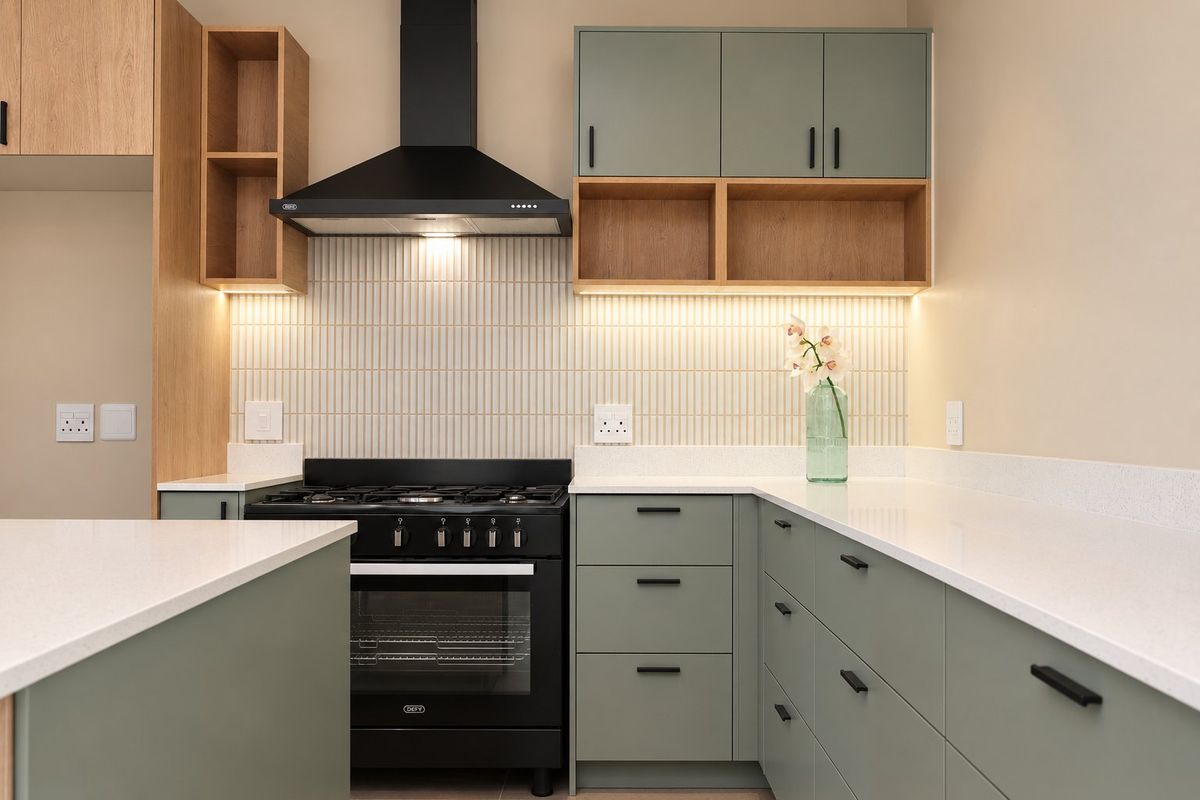 Modern kitchen featuring sage green cabinetry, white quartz countertops, a gas stove with extractor fan, and stylish vertical tiled backsplash with integrated lighting.