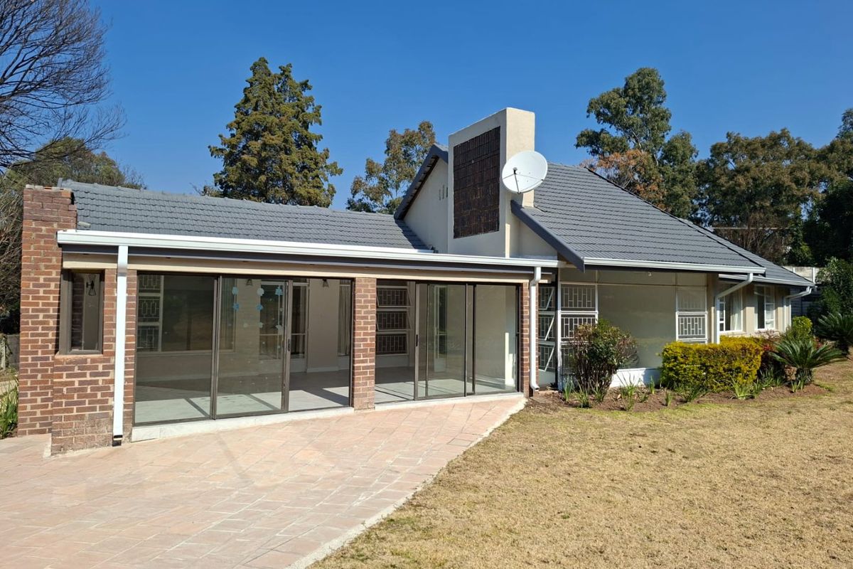 Rear view of the house featuring a paved patio area, sliding glass doors, and a tiled roof with a chimney.