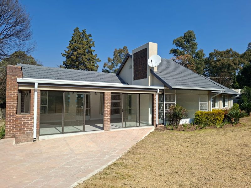 Rear view of the house featuring a paved patio area, sliding glass doors, and a tiled roof with a chimney.