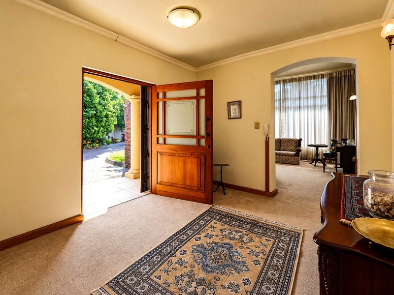 Welcoming entrance hall featuring a solid timber front door, carpeted flooring, and an elegant archway leading into the adjacent living area.