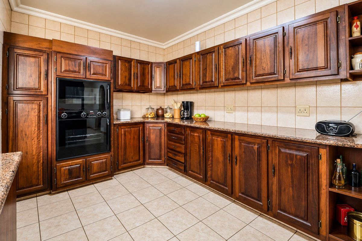 A traditional kitchen featuring dark wood cabinetry, granite countertops, tiled backsplash, and tiled flooring with a built-in oven.