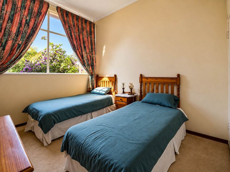 A well-lit bedroom featuring carpeted flooring and a large window that provides natural light and views of the garden.