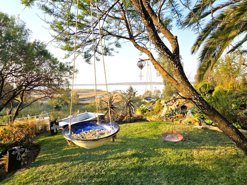 A lush, landscaped garden featuring mature trees and established greenery, offering a scenic view of the surrounding landscape and water.