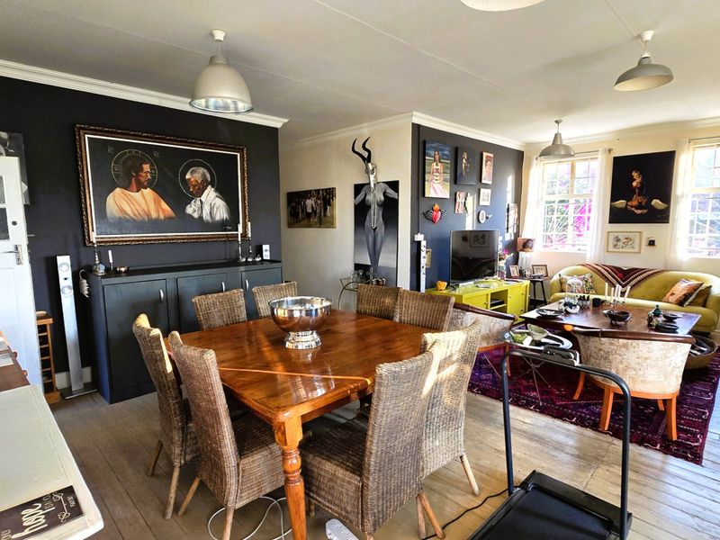 Spacious open-plan living and dining area featuring hardwood flooring, crown molding, and pendant lighting, offering a versatile layout for family living and entertaining.