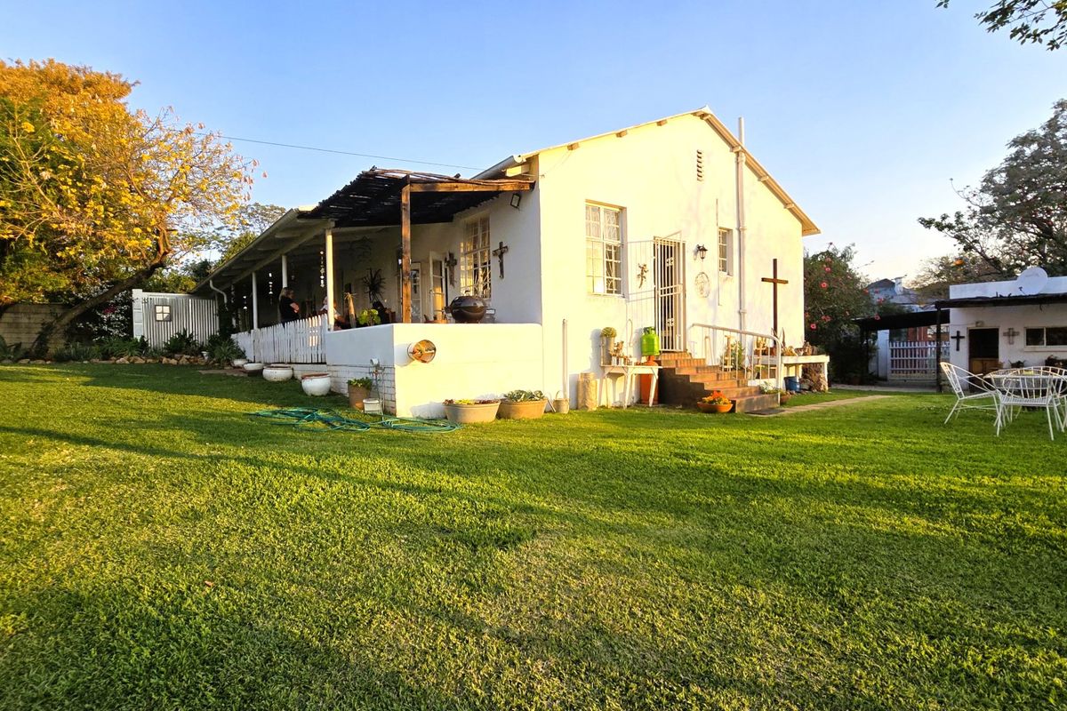 Rear view of the house featuring a covered patio, timber pergola, and a spacious garden area with established lawn.