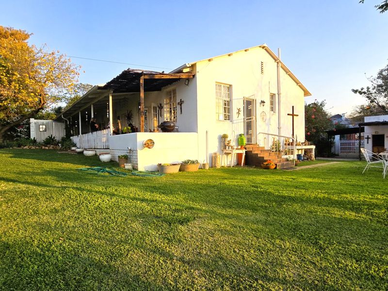 Rear view of the house featuring a covered patio, timber pergola, and a spacious garden area with established lawn.