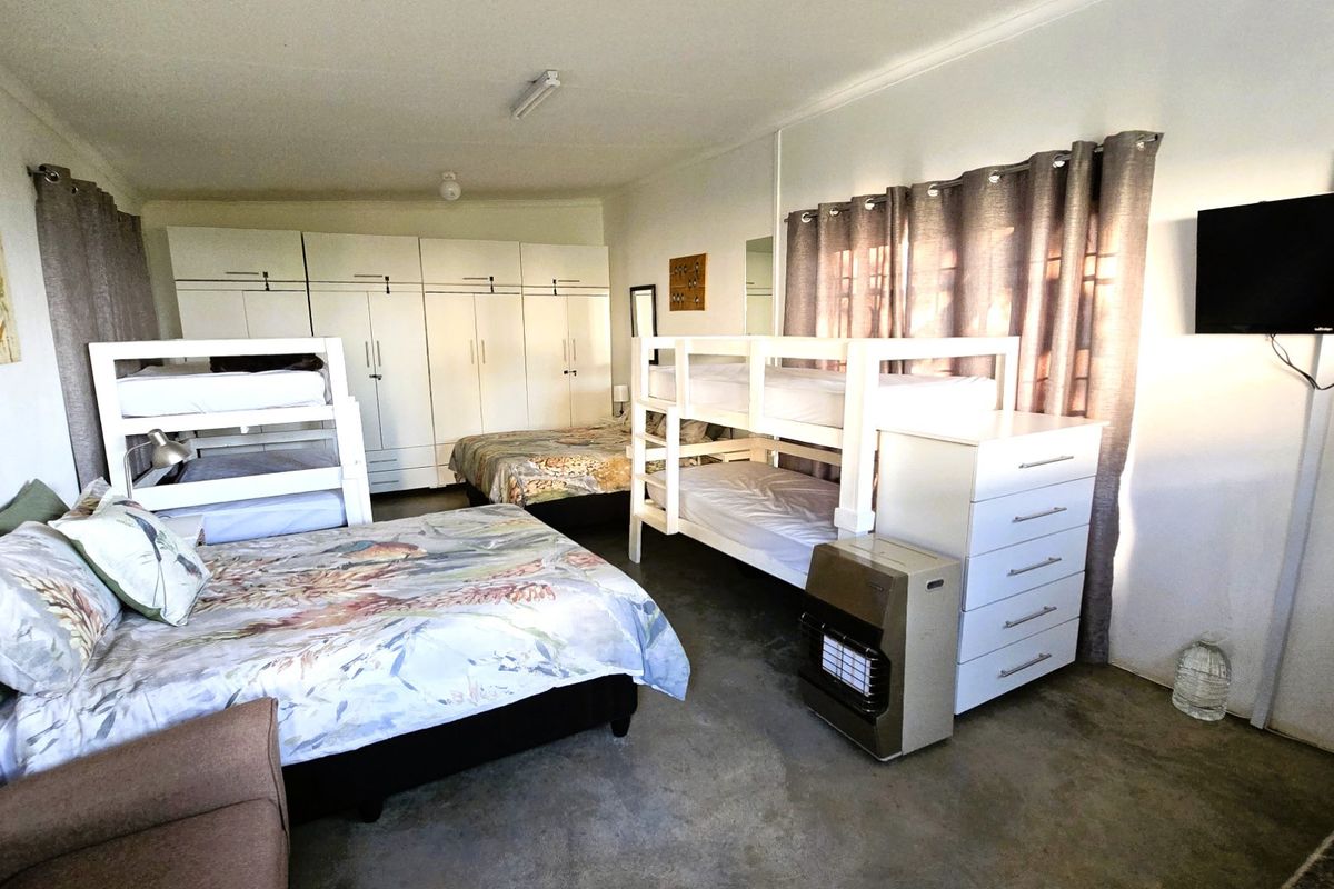 Spacious bedroom featuring built-in cupboards and concrete flooring, currently configured with multiple beds to accommodate several occupants.