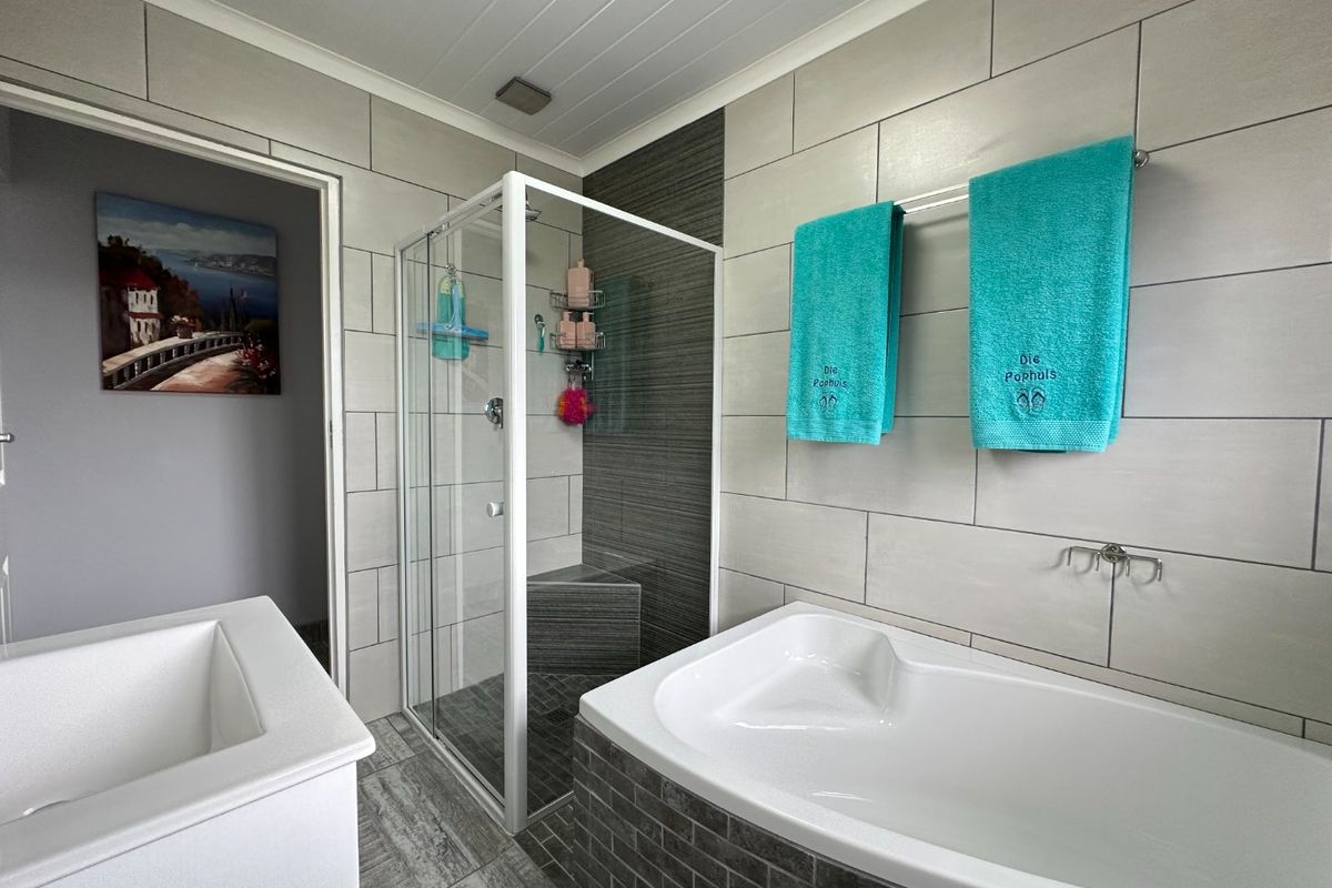 Modern bathroom featuring a built-in bathtub, a separate glass-enclosed shower, and contemporary neutral wall and floor tiling.