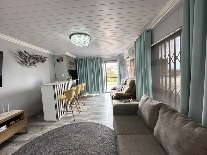 A well-maintained living area featuring a built-in bar, tiled flooring, tongue and groove ceiling, and direct access to an outdoor space via sliding doors.