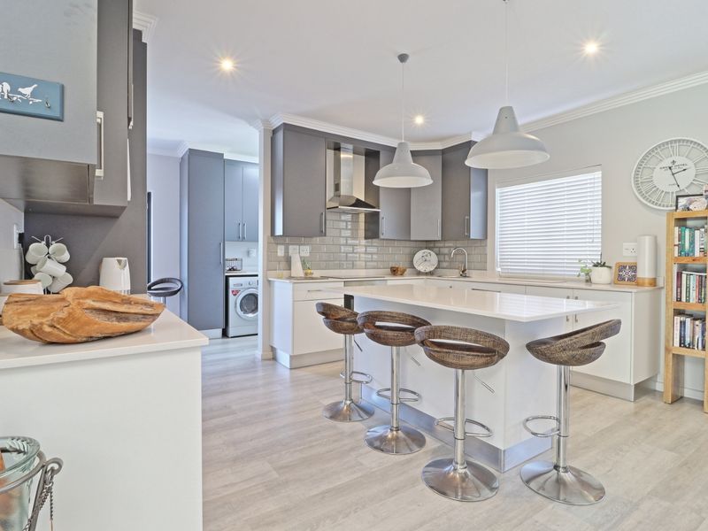 Modern open-plan kitchen featuring a central island with breakfast bar, sleek cabinetry, quartz countertops, and high-quality finishes throughout.