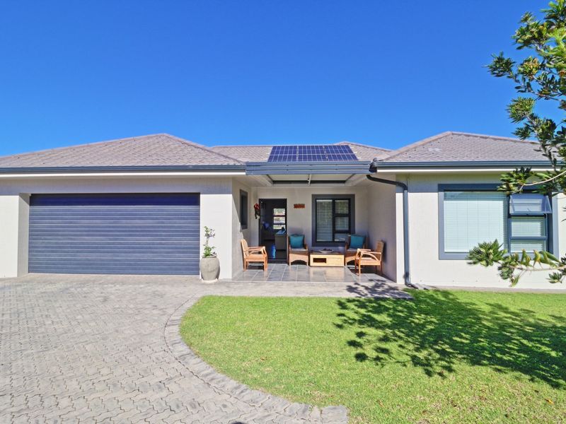 Front elevation of a single-story house featuring a paved driveway, integrated garage, solar panels, and a well-maintained front lawn.