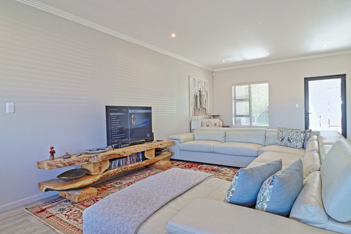 A bright and well-maintained living room featuring recessed downlighting, neutral wall finishes, and direct access to the exterior.