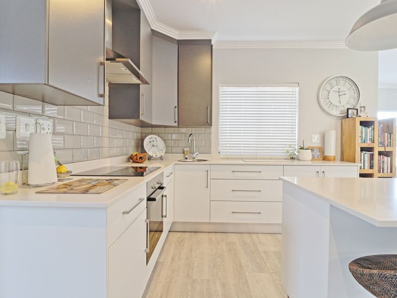 Modern kitchen featuring sleek two-tone cabinetry, quartz countertops, subway tile backsplash, integrated appliances, and a functional central island.