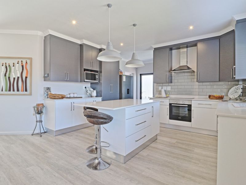 Modern kitchen featuring a central island, quartz countertops, subway tile backsplash, built-in appliances, and sleek cabinetry with contemporary pendant lighting.