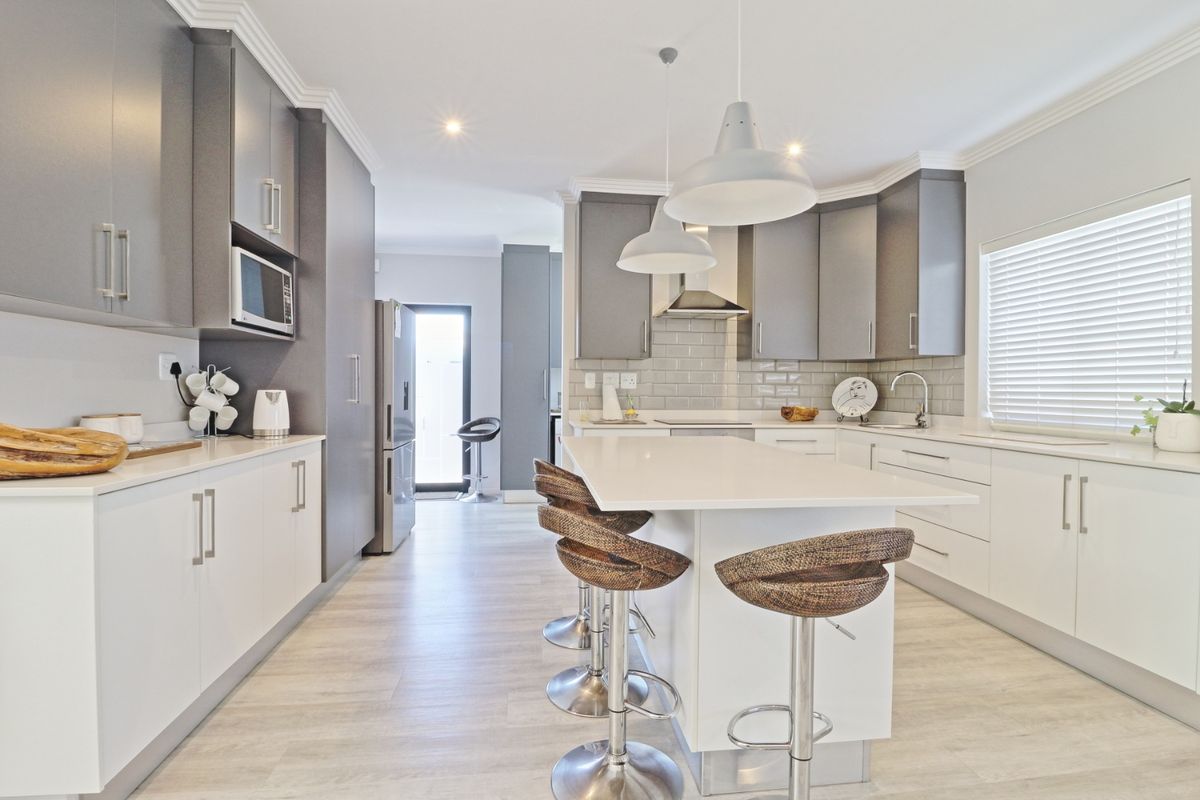 Modern kitchen featuring a central island with quartz countertops, subway tile backsplash, sleek cabinetry, and high-quality integrated appliances.