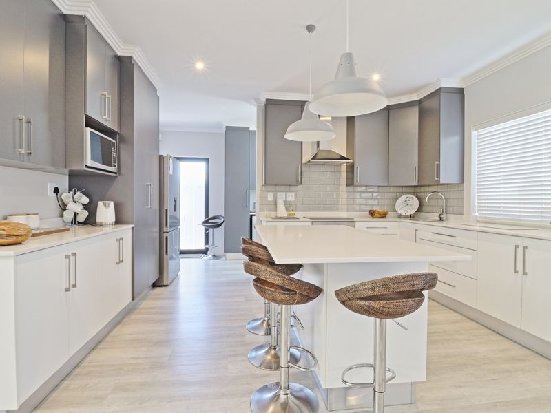 Modern kitchen featuring a central island with quartz countertops, subway tile backsplash, sleek cabinetry, and high-quality integrated appliances.
