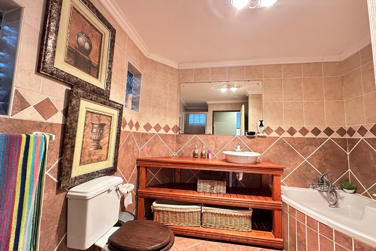 A functional bathroom featuring ceramic wall and floor tiling, a wooden vanity with a vessel sink, and a built-in bathtub.