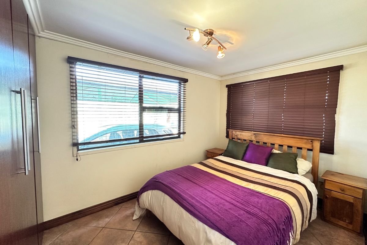 A bedroom featuring tiled flooring, built-in cupboards, and venetian blinds, providing a functional and well-lit space.