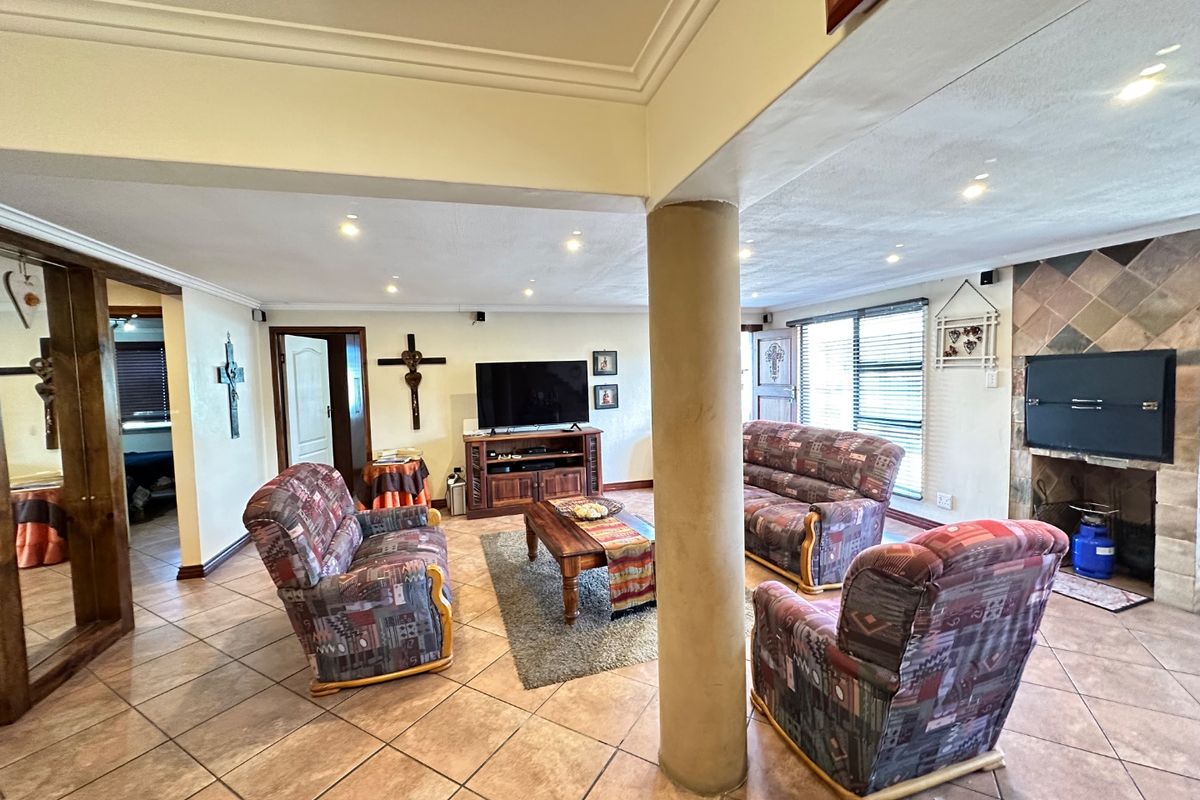 Spacious living room featuring tiled flooring, recessed lighting, a central structural column, and a built-in fireplace with tiled surround.