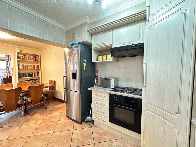 Open plan kitchen and dining area featuring light-toned cabinetry, built-in oven and hob, and tiled flooring throughout.