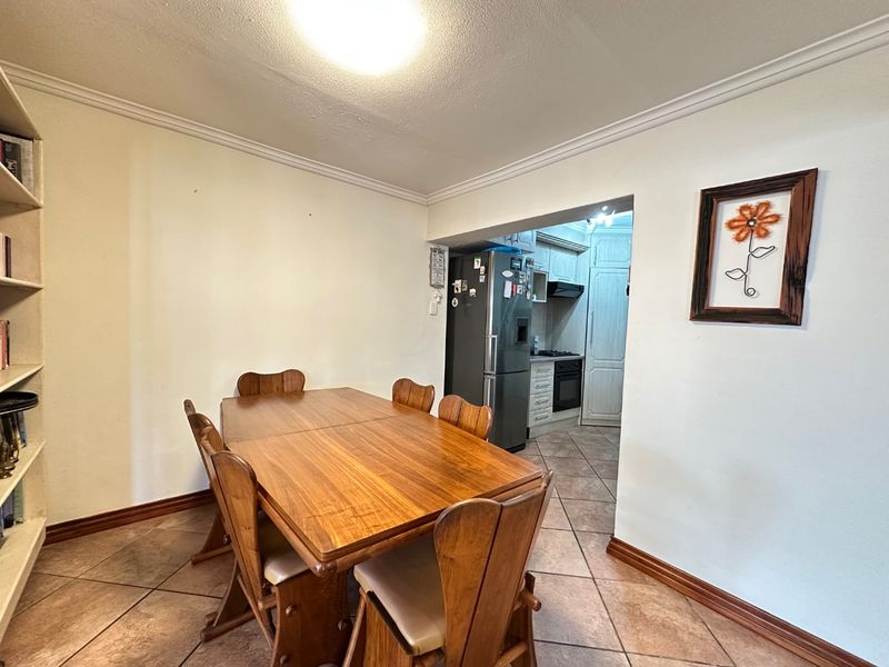 Open plan dining area featuring tiled flooring and crown molding, with a direct view into the adjacent kitchen space.