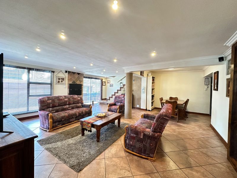 Spacious open-plan living and dining area featuring tiled flooring, recessed lighting, a central structural column, and a built-in fireplace.