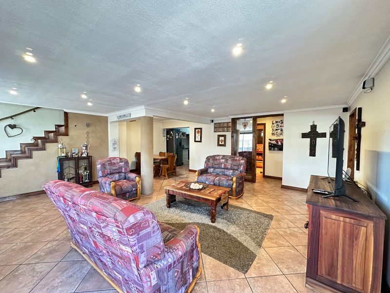 Spacious open-plan living area featuring tiled flooring, recessed lighting, and a staircase, providing a versatile layout that connects to the kitchen and dining space.