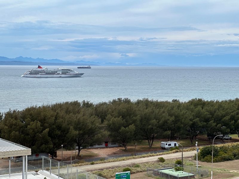A scenic elevated view overlooking the coastline, featuring a clear ocean horizon with ships and surrounding natural landscape.