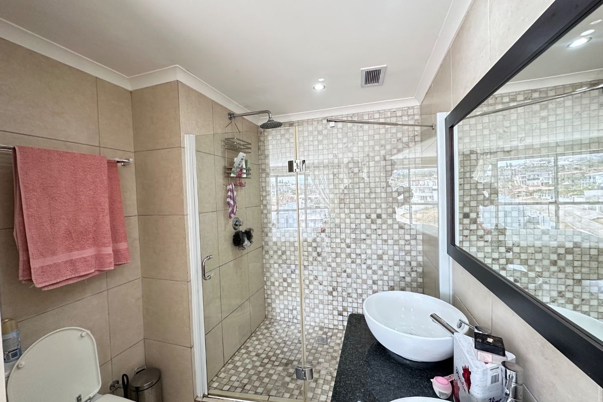 Modern bathroom featuring a walk-in shower with mosaic tiling, a granite-topped vanity with dual basins, and neutral wall tiles.
