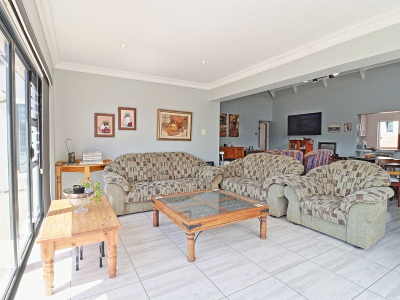 Spacious open-plan living area featuring tiled floors, recessed lighting, and seamless flow to the kitchen and outdoor patio through large sliding glass doors.