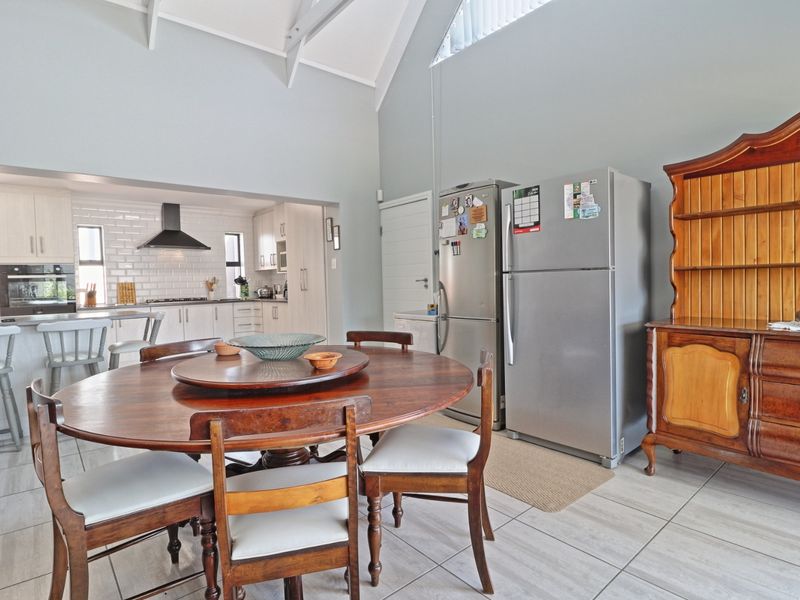 Open plan kitchen and dining area featuring vaulted ceilings, modern cabinetry, subway tile backsplash, and neutral ceramic floor tiles.