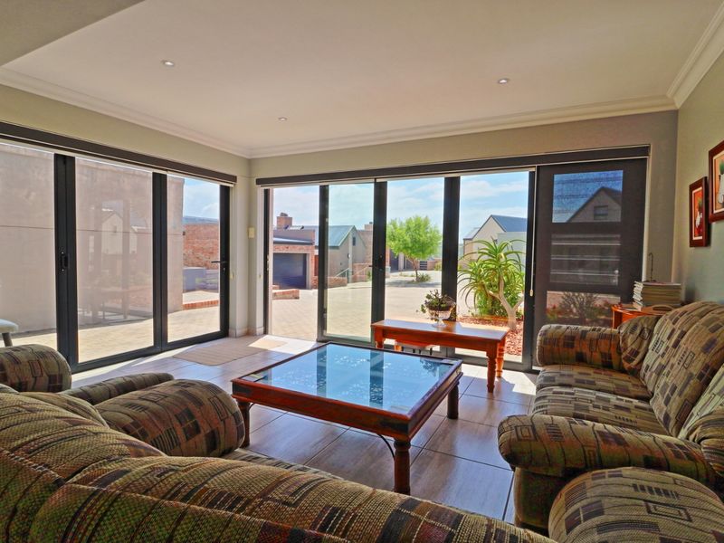 A bright living room featuring large aluminium sliding doors that provide ample natural light and direct access to the exterior.