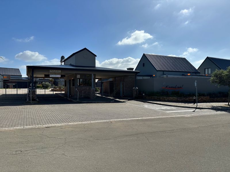 The main entrance and security gatehouse of the residential estate, featuring paved access and secure perimeter walling.
